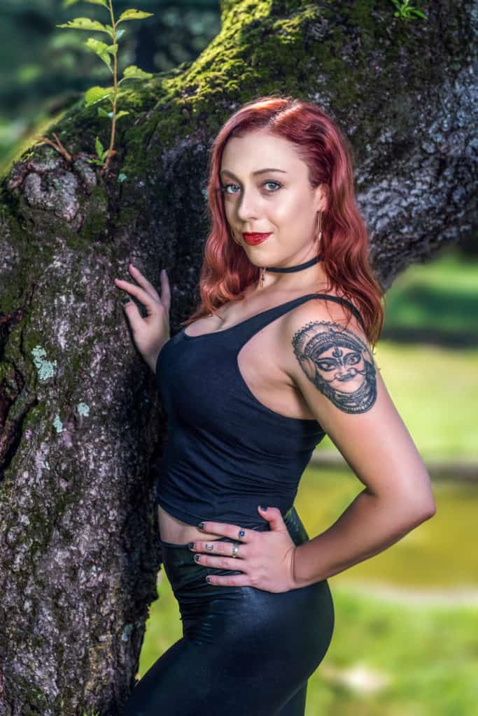 environmental portrait, female in a black outfit in the park next to the tree